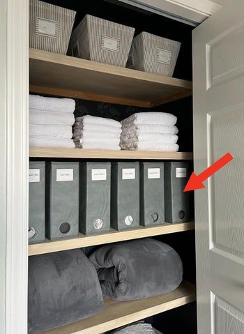 A tidy closet featuring labeled bins and neatly arranged towels and blankets.