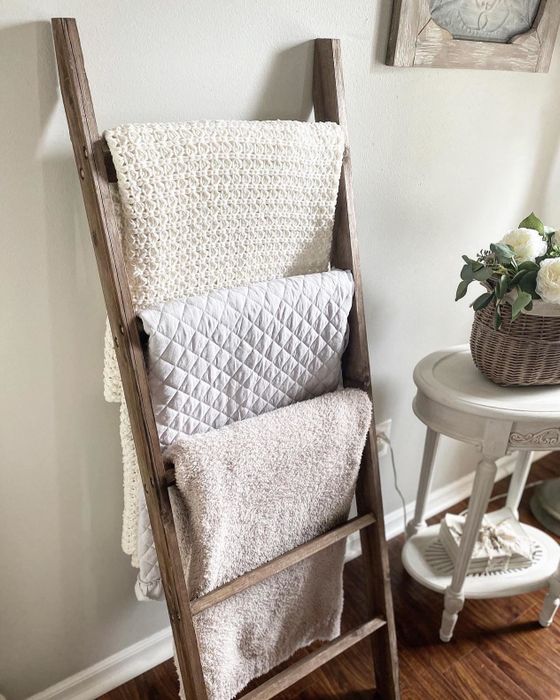 A reviewer showcases the ladder with three cozy blankets draped over it.