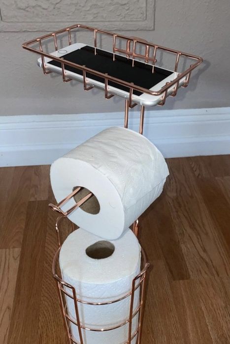 A reviewer shares a photo of their toilet paper stand with their phone resting on the top shelf of the holder.