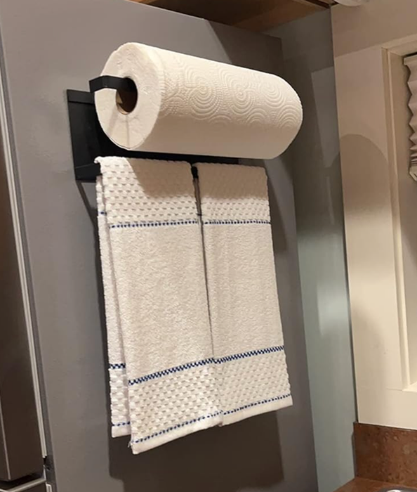 A large paper towel roll mounted above a smaller towel hanging from a magnetized bar on the fridge