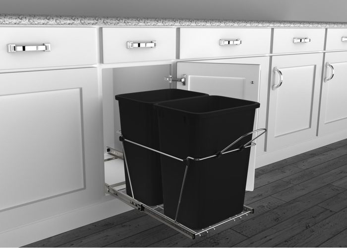 Discreet kitchen trash bins within a cabinet, featuring a pull-out sliding system that helps save space and maintains a sleek, tidy look.