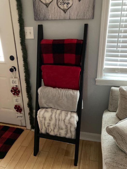 A reviewer displays the black ladder with four blankets hanging from it.