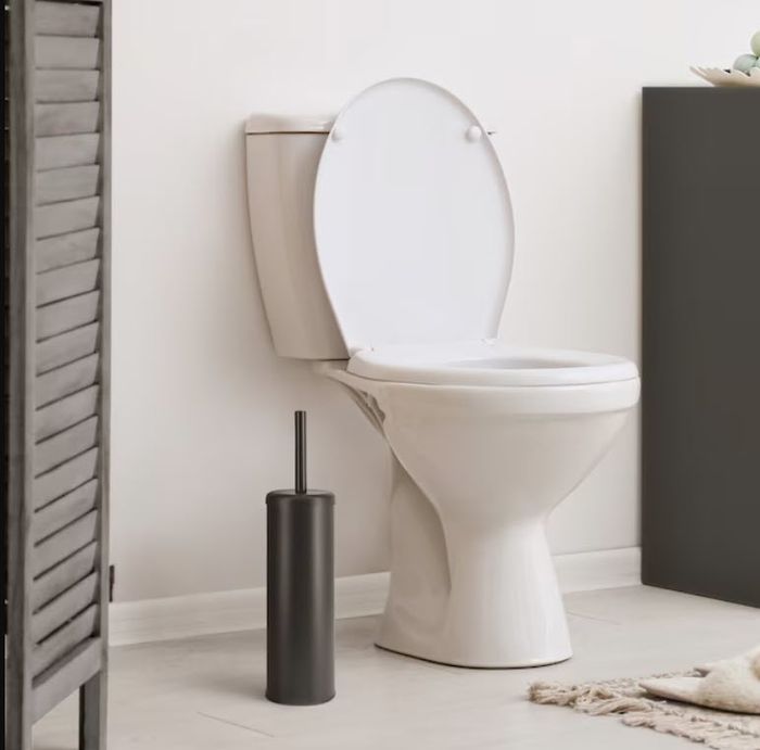 A modern white toilet with the lid raised, paired with a black toilet brush holder on the floor next to it, creating a clean and minimalist bathroom atmosphere.