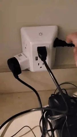 A reviewer turning the light on and off on the charger, with multiple items plugged in