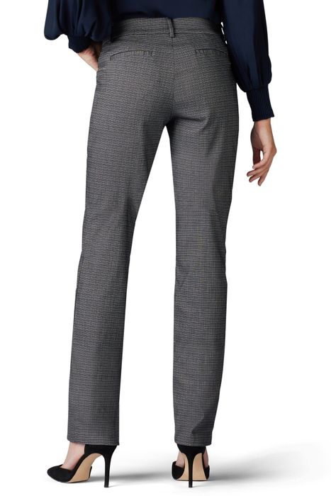 A model styled in straight-leg patterned pants and a dark, long-sleeve top, completed with black high heels, posed from behind