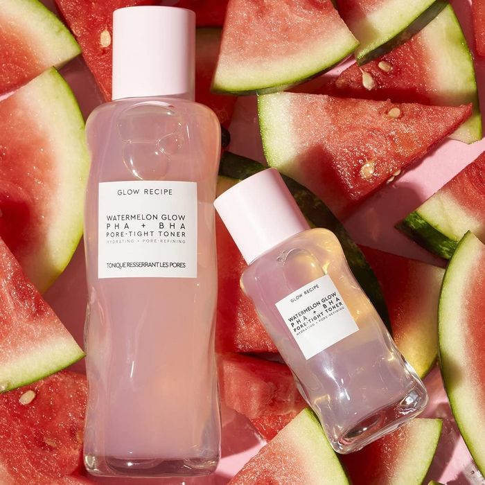 Two bottles of the toner in different sizes resting on watermelon slices.