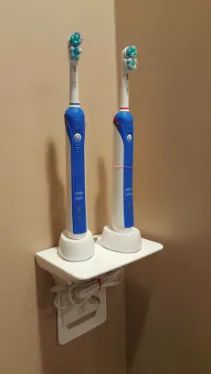A reviewer’s photo showing two electric toothbrushes neatly stored on the outlet shelf.