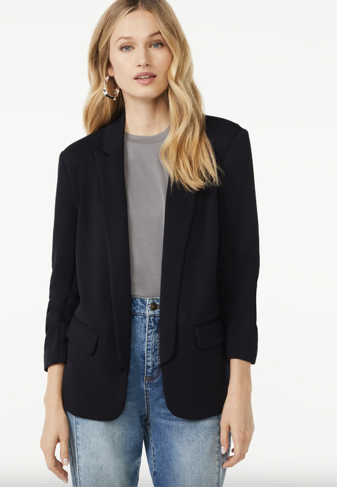 A woman wearing a black blazer, gray shirt, and jeans, achieving a chic yet relaxed style. Perfect for shopping trips or daily outings while still looking polished.