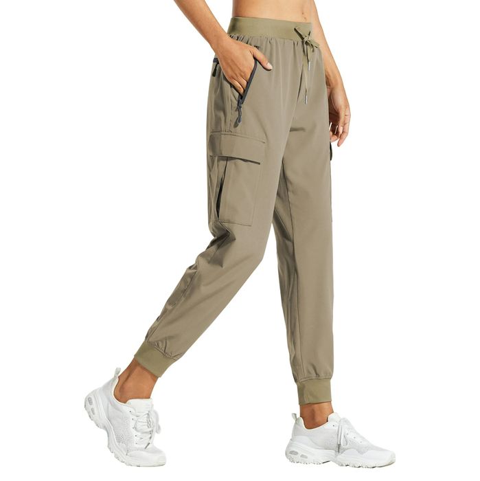 Individual sporting jogger pants with zipper pockets and white sneakers, captured in a side profile