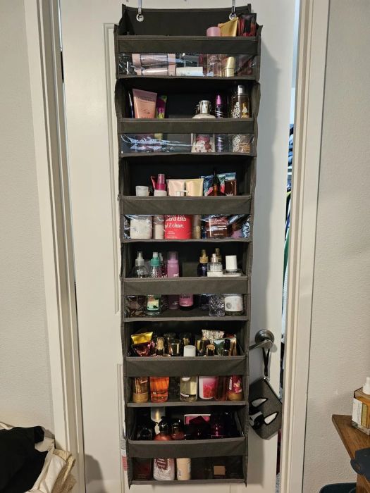Hanging organizer on a door, filled with various beauty products like lotions, perfumes, and skincare items, neatly arranged in separate compartments