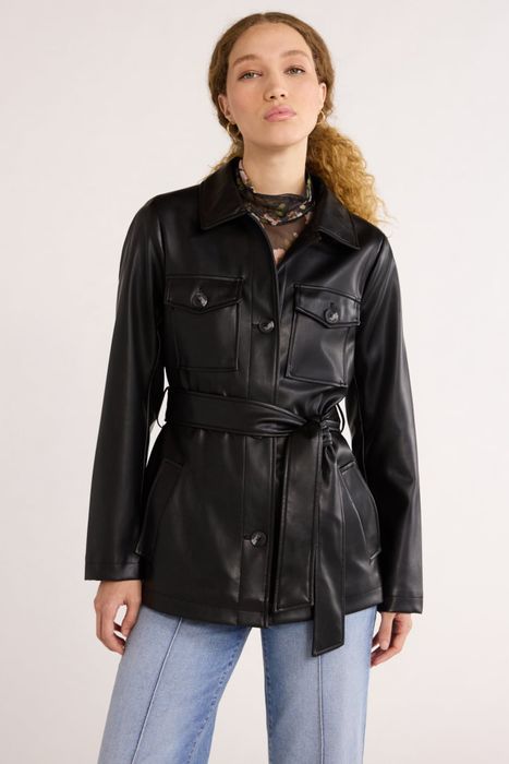 A person wearing a belted leather jacket and light denim jeans, posing against a simple backdrop.