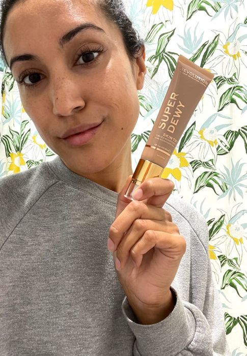 Jasmin holding the tinted moisturizer in shade Medium.