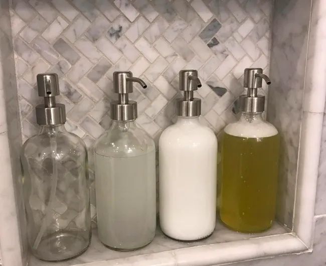 A customer review photo showing four soap dispensers neatly arranged in their shower.
