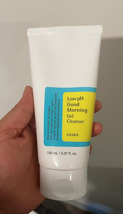 A reviewer holding the cleanser in their hands.