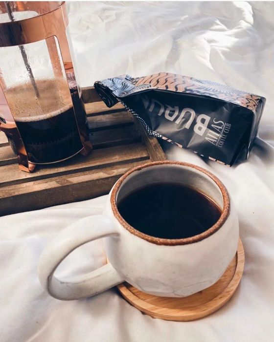A freshly brewed cup of coffee sits beside a French press.