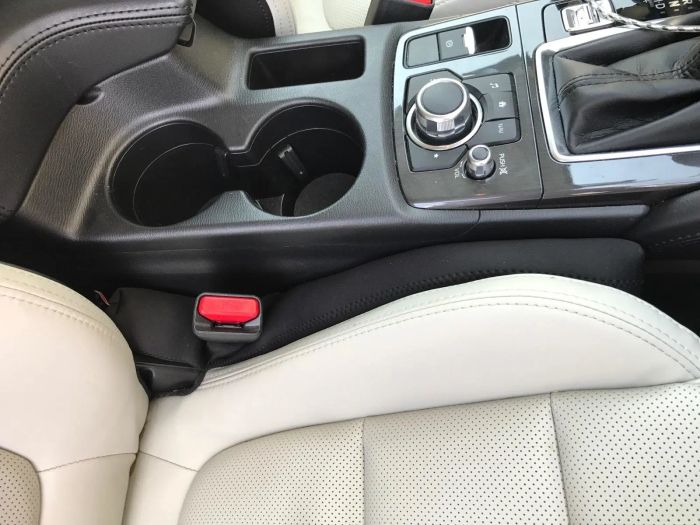 A black seat gap filler securely placed between the car seat and console.