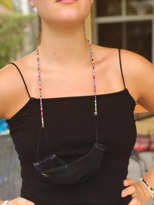 A model wears a face mask like a necklace, showcasing the chain's stylish functionality.
