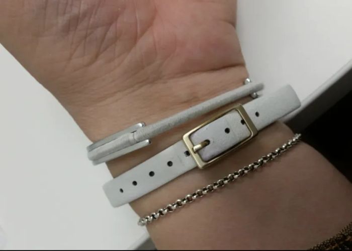 A reviewer wearing a silver bangle with a gray hair tie threaded through it.