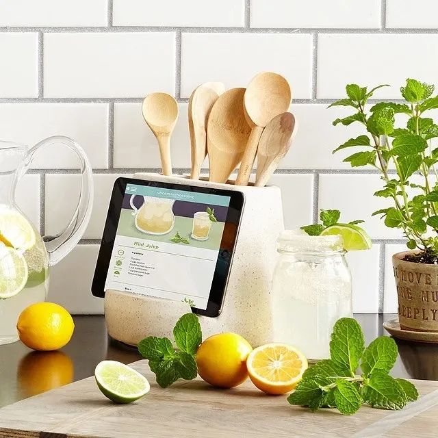 A utensil holder with an iPad propped up on it, ready for some culinary guidance or entertainment.