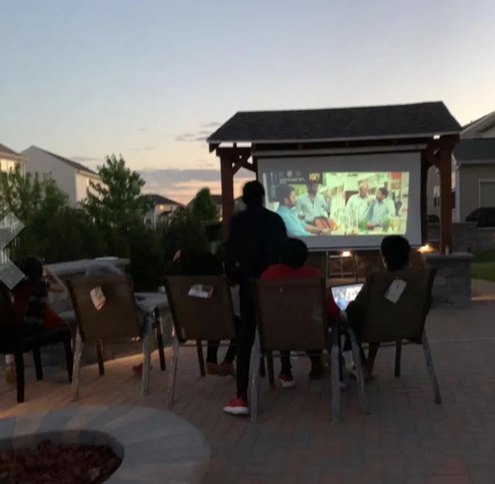 Another reviewer shows the projector being used outdoors, bringing the magic of cinema to an open-air setting.