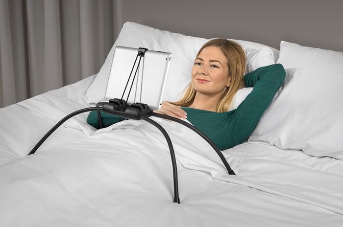 A model demonstrating the use of the black tablet holder while lying in bed.