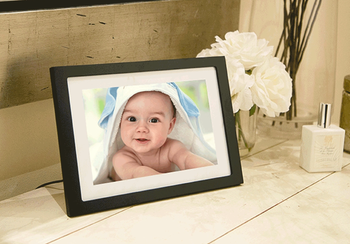 The photo frame plugged into the wall, showcasing an image of a baby on its screen.