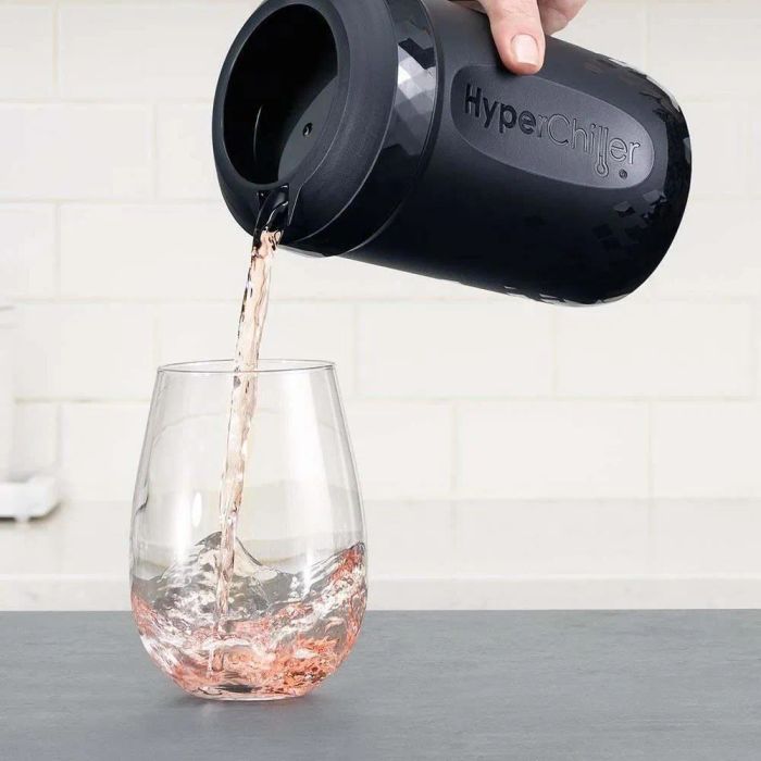 A hand pouring rosé from the HyperChiller into a glass.