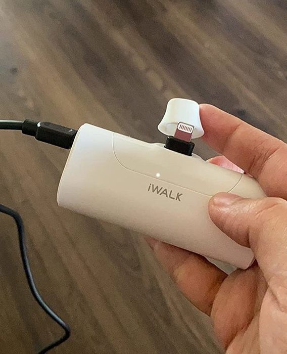 A reviewer holding the white portable charger in their hand.
