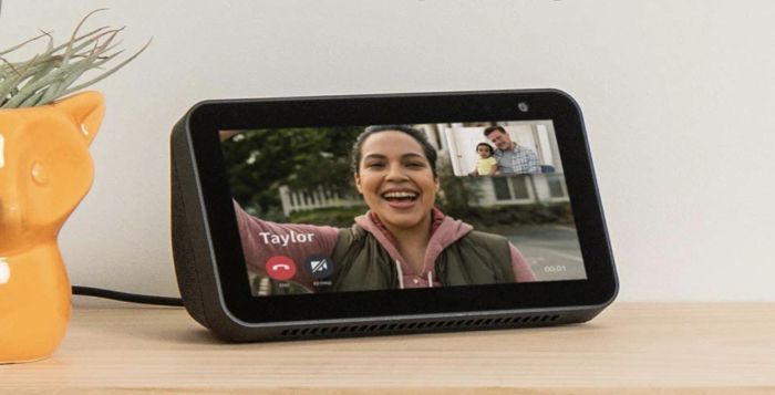 A person appears on the screen of an Amazon Echo Show 5, video chatting with their family from miles away.
