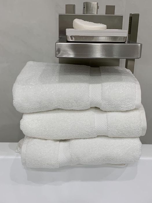 The white towels draped over the edge of a bathtub