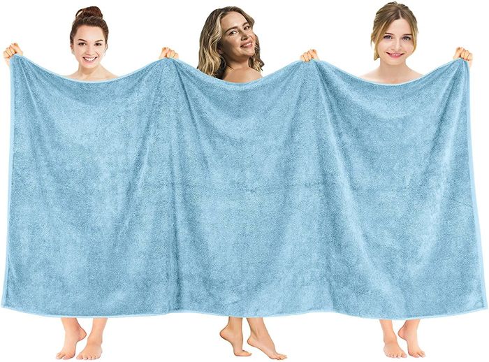 Three women proudly displaying the oversized towel