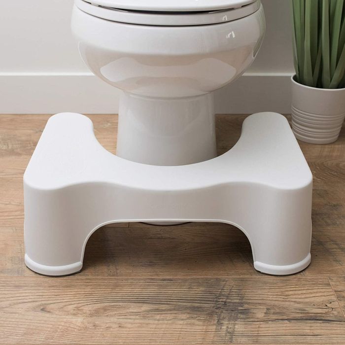 The white Squatty Potty placed in front of a toilet