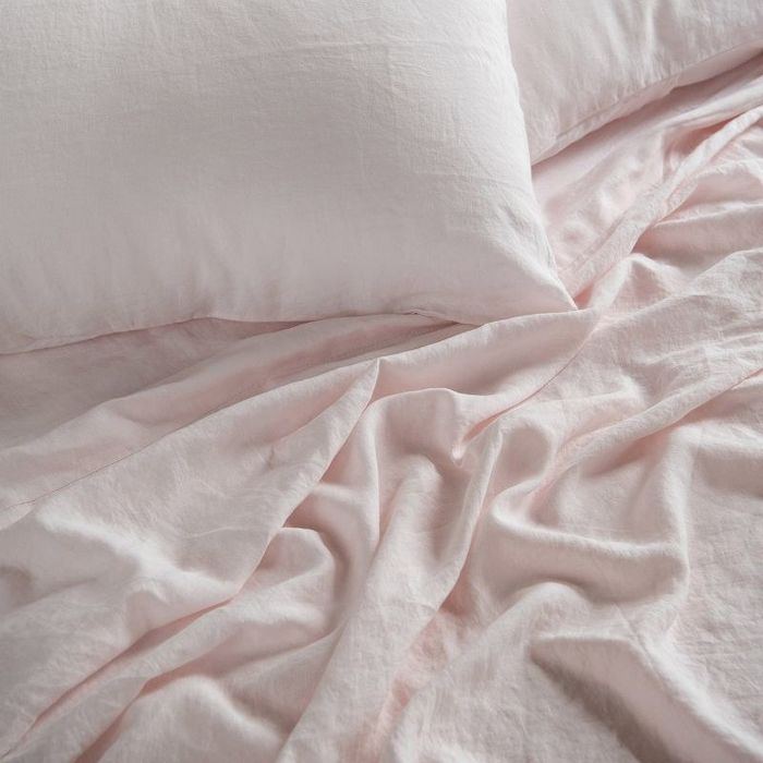 Soft light pink linen sheets and pillows arranged beautifully.
