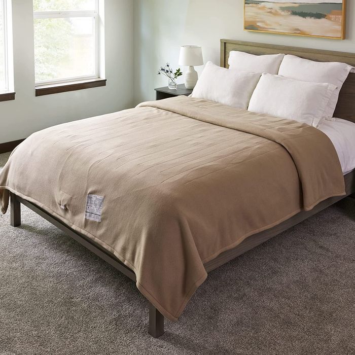 A picture showing a beige blanket draped over a bed