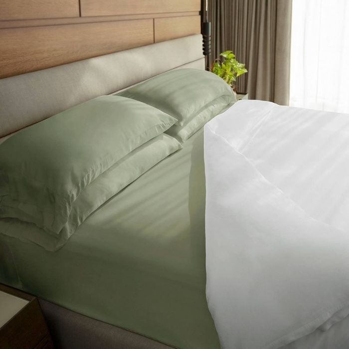A freshly made bed featuring four pillows with a duvet pulled back to reveal the bed beneath.