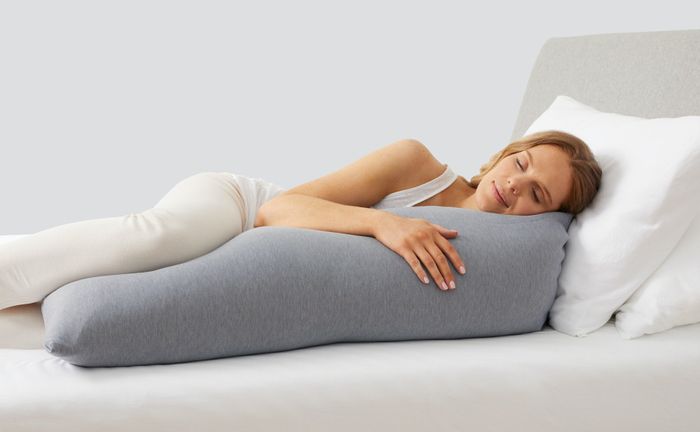 A model lying down with the gray body pillow