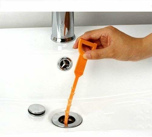 A hand guiding the drain snake into a clogged pipe