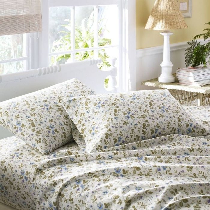 a white sheet set adorned with small green and blue floral accents