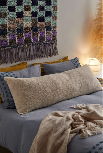 Image of the beige body pillow resting comfortably on a bed