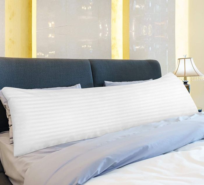 Photo of a white body pillow resting on a bed