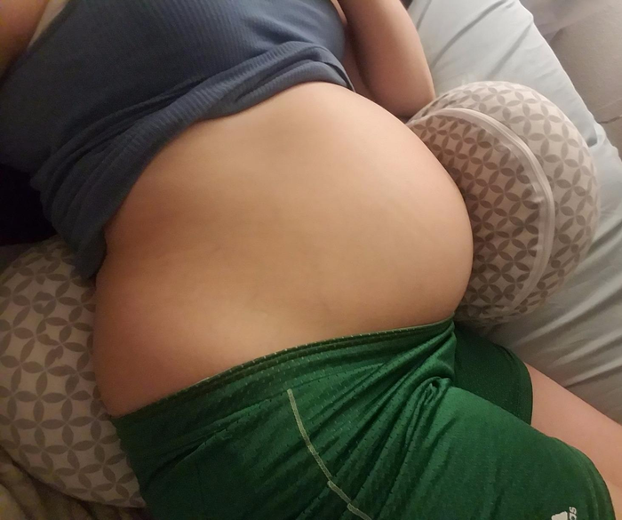 Reviewer resting on the gray and white Boppy pregnancy pillow