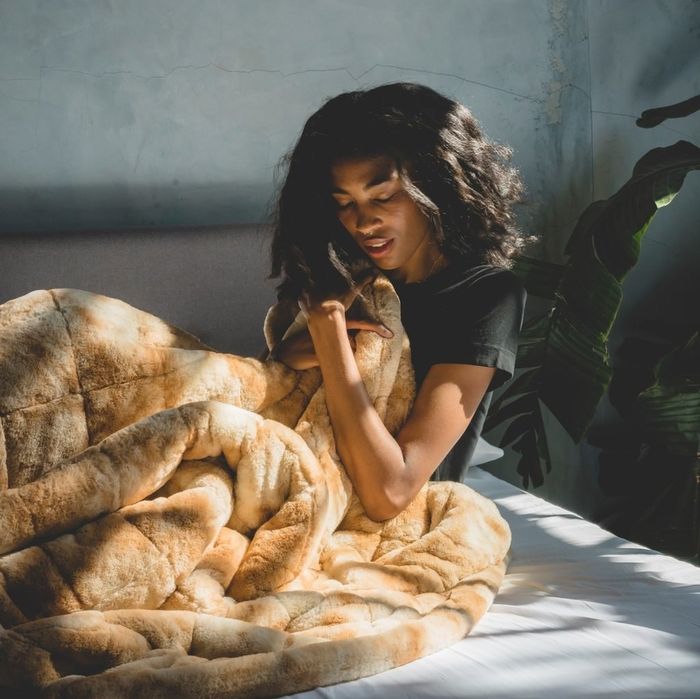 A model enjoying the warmth of the honey-colored weighted blanket