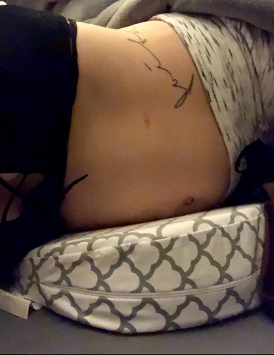 Reviewer resting on the gray and white pregnancy wedge pillow