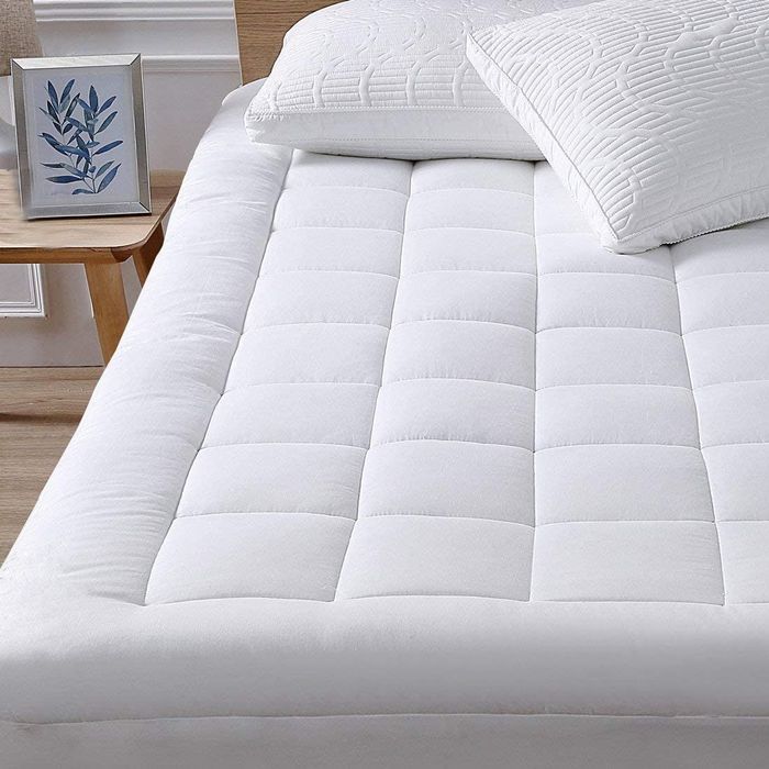 The white mattress pad, snugly fitting over the mattress,