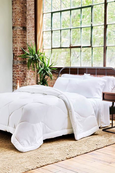The soft, white comforter spread across a bed