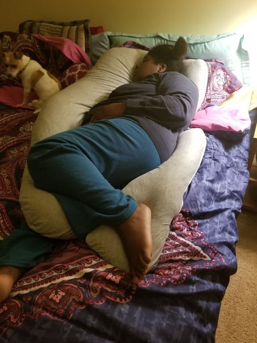 Reviewer lying down on a light gray body pillow