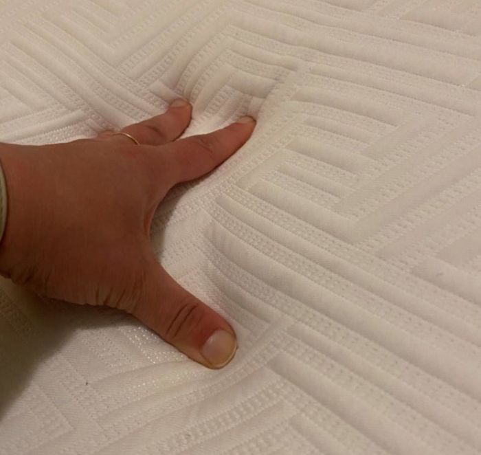An Amazon reviewer gently touching the queen-sized mattress to assess its feel.