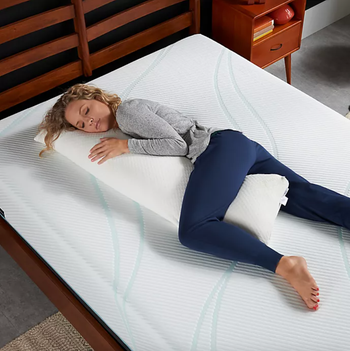 An image of the model lying on the bed with the white pillow.