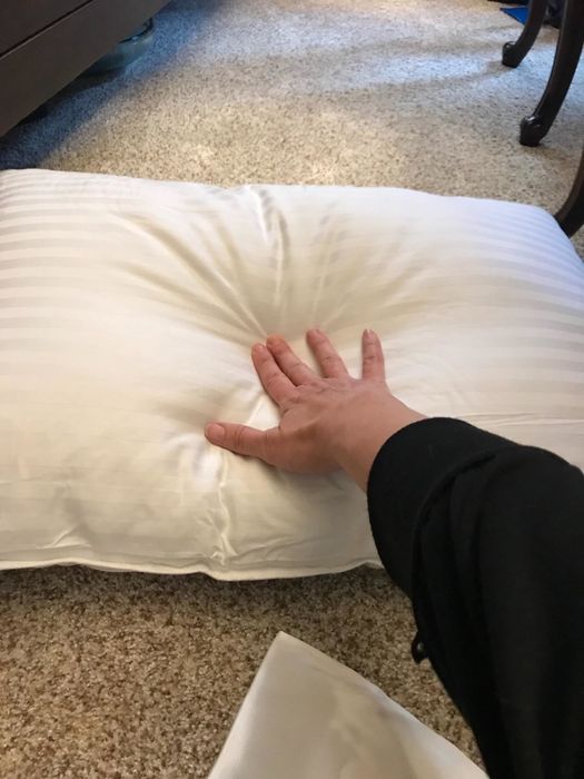 A reviewer pressing the pillow to demonstrate how plush it is
