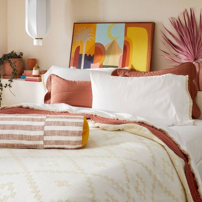 The sheets in white with tan fringe elegantly arranged on a bed.